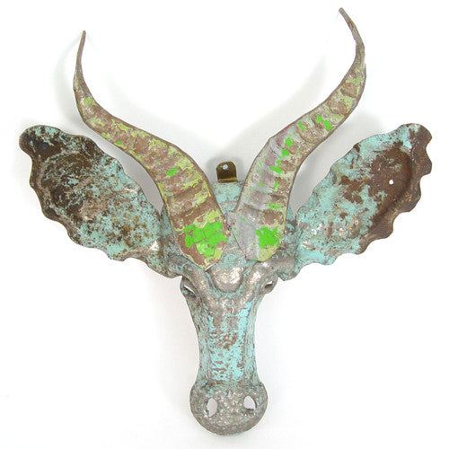 Decorative metal bull head with green patina on a white background