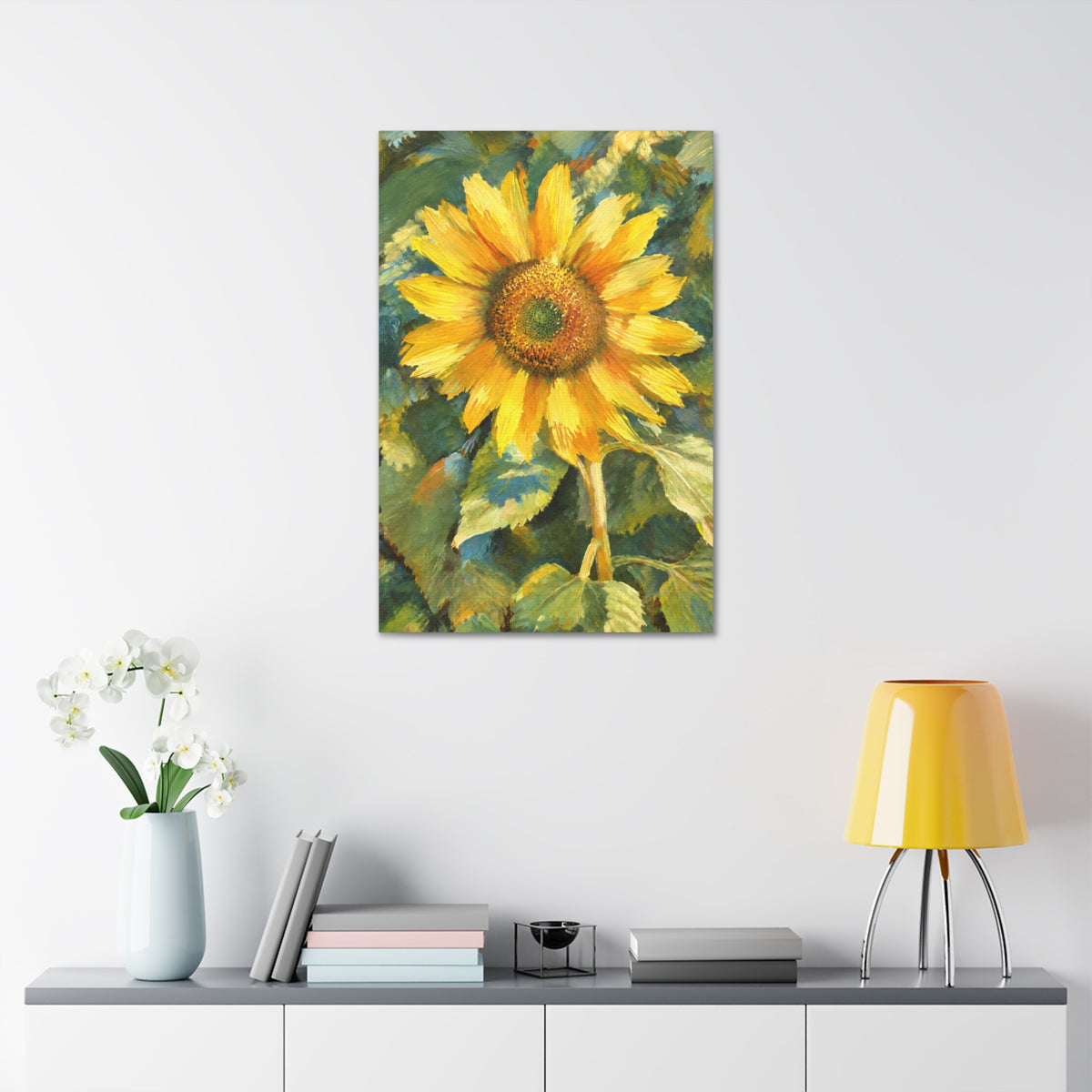 Sunward sunflower canvas above a gray cabinet styled with white orchids, books, and a yellow lamp.