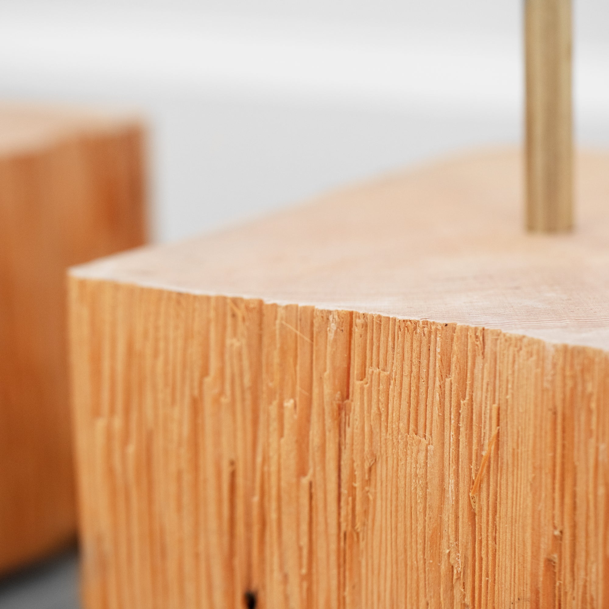 Close-up of two raw pine wood cube stem plant holders with a slim brass rod insert, showing natural wood grain texture on a light grey background