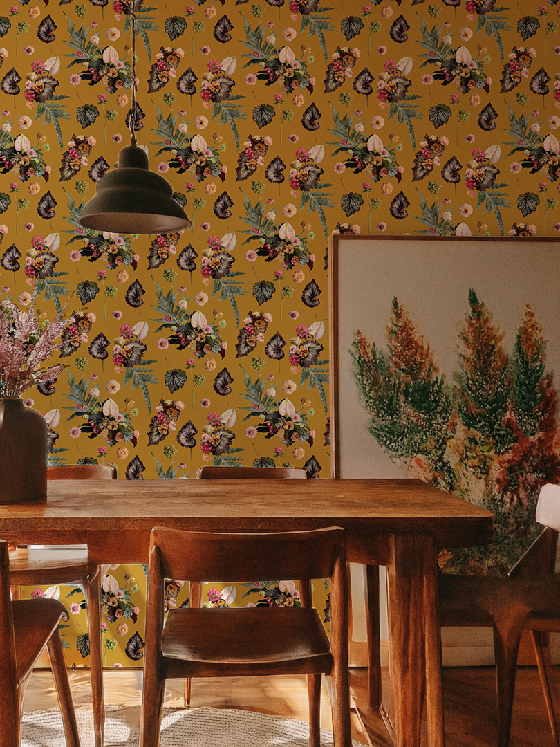 The Little Branch Wallpaper in mustard installed in a moody dining room — painterly botanical collage of florals and foliage by Samantha Santana, styled with a dark wood table and botanical art print