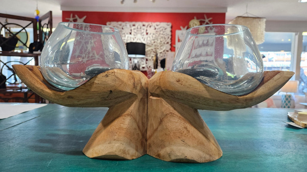 carved wooden hands with two glass terrariums on a table