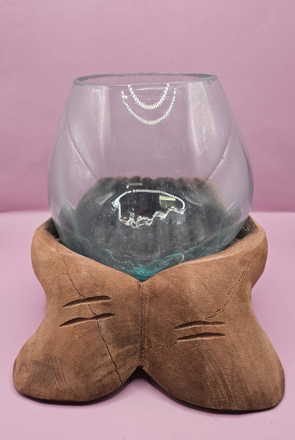 Glass bowl with a wooden base on a pink background